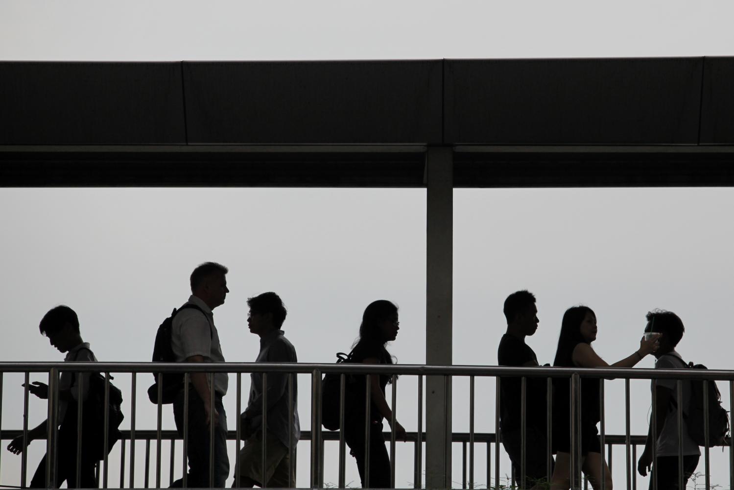 Office workers cross a pedestrian bridge in the Siam area. The Covid-19 pandemic is taking a toll on businesses. Wichan Charoenkiatpakul