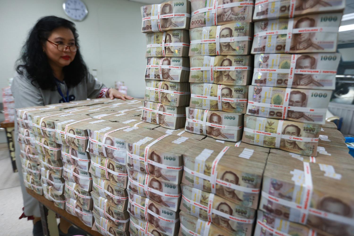 A Bangkok Bank employee gathers stacks of thousand-baht banknotes. A senior BoT official said banks have a sufficient capital buffer in the event of higher past-due payments and debt restructuring. (Photo by Somchai Poomlard)