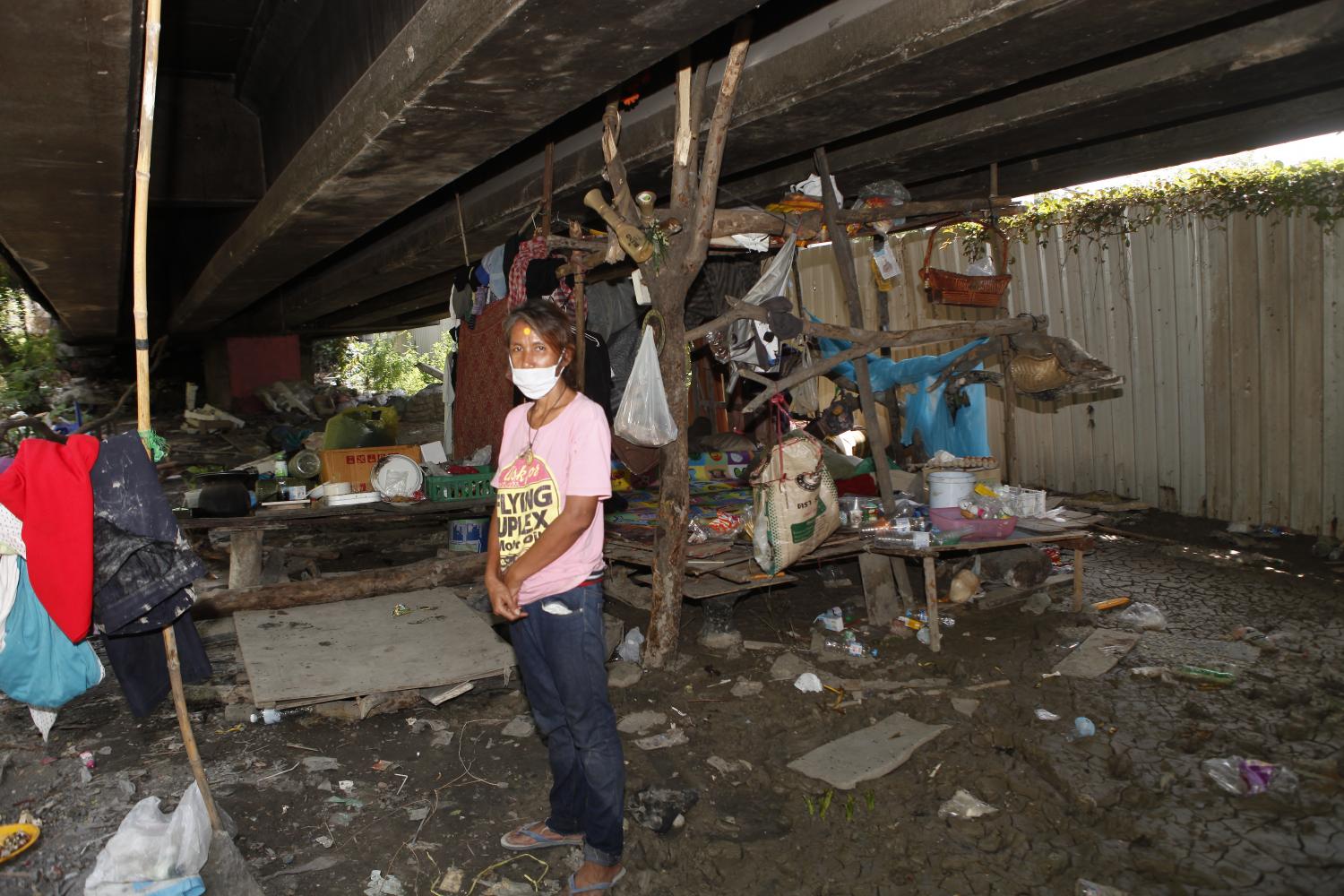 Orathai Srisawas, a deaf woman who lives in a community underneath the Rama IX expressway, stands in front of her shelter. photos by Nutthawat Wichieanbut