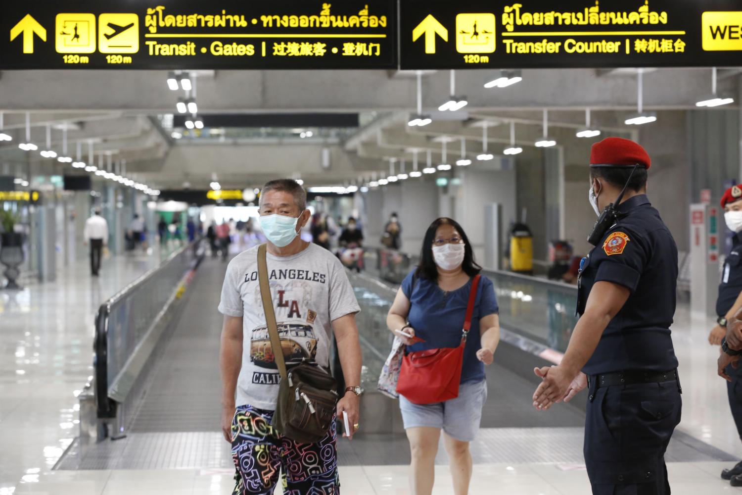 Tourists and officers at Suvarnabhumi airport wear face masks. Travellers entering Thailand via air travel could be charged a new tax as part of their tickets. (Photo by Pornprom Satrabhaya)