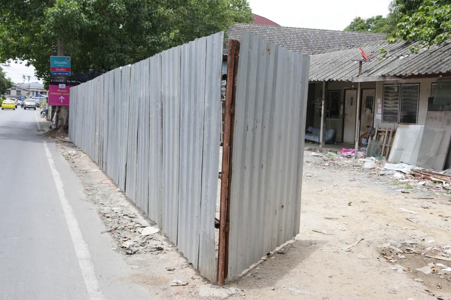 A fence made of corrugated sheets is erected to prevent entry to a land plot adjacent to Wat Suan Kaeo in Nonthaburi. The temple has lost the legal fight over ownership of the land and the plot's occupants face an eviction order. (Photo by Apichit Jinakul)