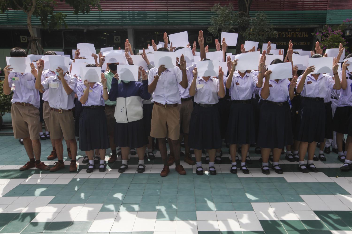 Students from several schools in and outside of Bangkok give the three-fingered salute in a symbolic protest against the government. Some also tied white ribbons to their bags to show their opposition. The Education Ministry has allowed the students to express their political views on school premises. (Photos by Samut Kongwarakom, Arnun Chonmahatrakool and the internal security operations command)