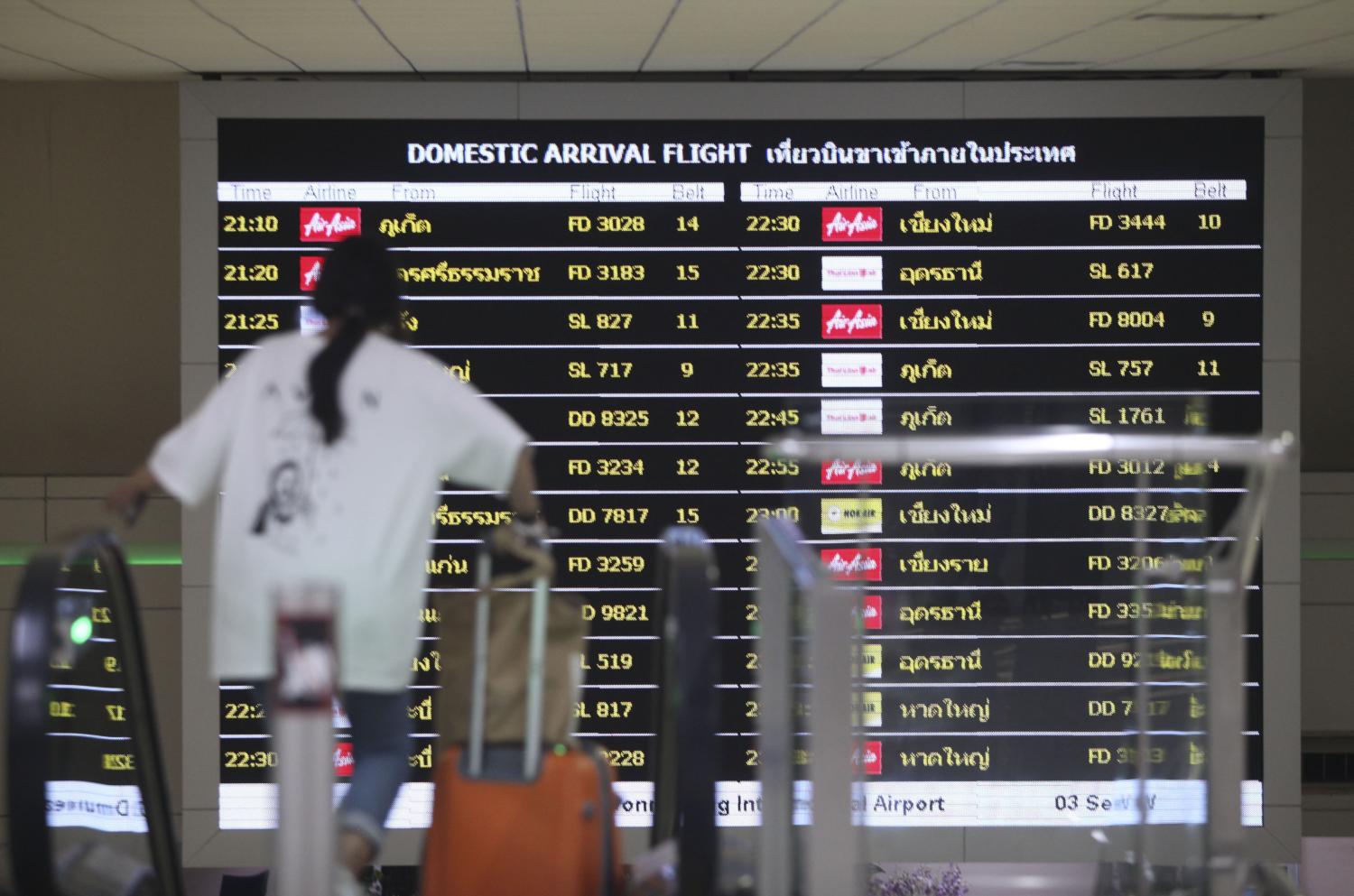 A passenger walks past a flight schedule display at Don Mueang airport. The Thai Travel Agents Association expects tourism will improve by June at a gradual pace.