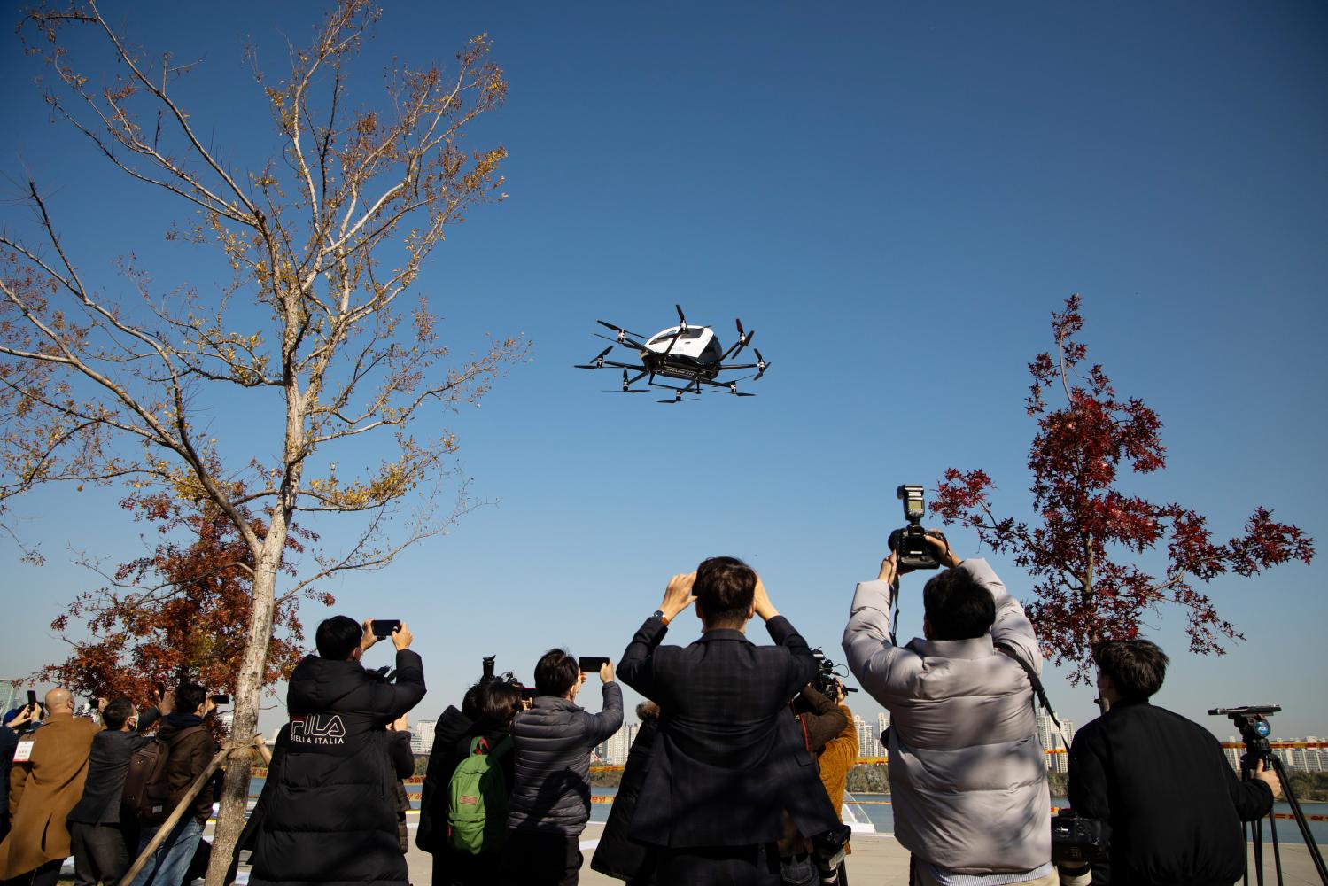 Members of media take photographs and film the EHang 216 during a demonstration in Seoul on Wednesday. (Bloomberg photo)