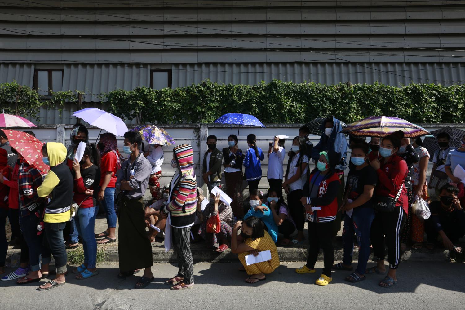 People wait patiently in a queue to receive assistance at a Covid-19 testing centre in Baan Eua Arthorn Tha Chin in Samut Sakhon on Tuesday. (Photo by Arnun Chonmahatrakool)