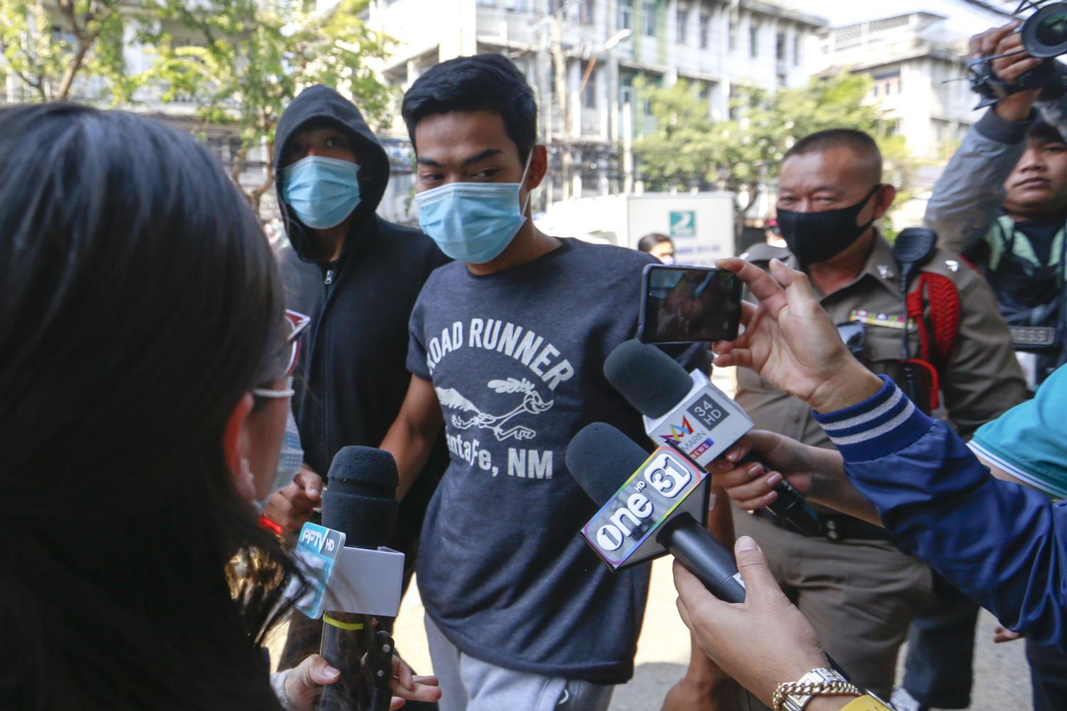 Chatree Srisombat, 19, (in the 'Runner' shirt) and Noppakao Obthom, 26, (in the hooded jacket) are escorted to Wat Phraya Krai police station on Wednesday. Mr Chatree was charged with selling the fatal 'k-powdered milk' blend and Mr Noppakao with possessing the drug. (Photo by Arnun Chonmahatrakool)