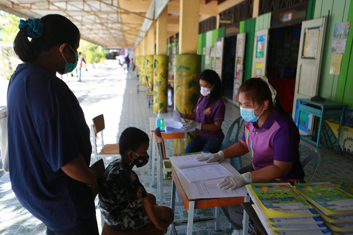 In this Jan 5 photo, a student and his mother drop by at his school in Samut Prakan to pick up educational material to study at home after the government ordered school closures in response to a new wave of Covid-19 infections. Somchai Poomlard