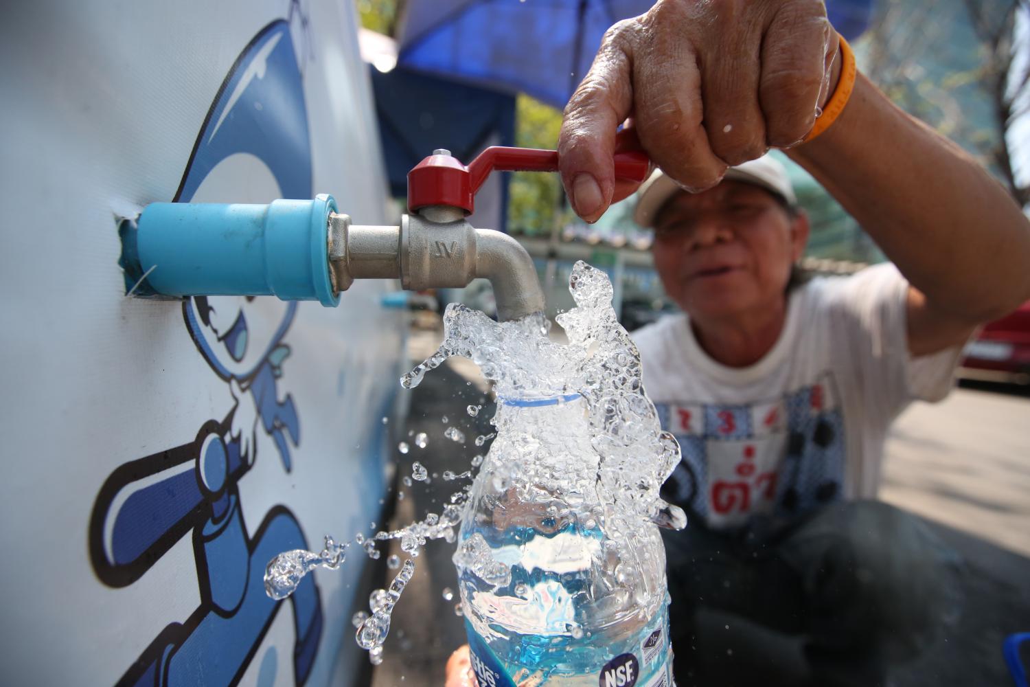 A Rot Fai community resident turns on a tap to fill a bottle with water at the Metropolitan Waterworks Authority headquarters in Bangkok. The government has been urged to tackle a saltwater intrusion problem after the amount of sodium in tap water exceeded safe levels. (Photo by Pattarapong Chatpattarasill)