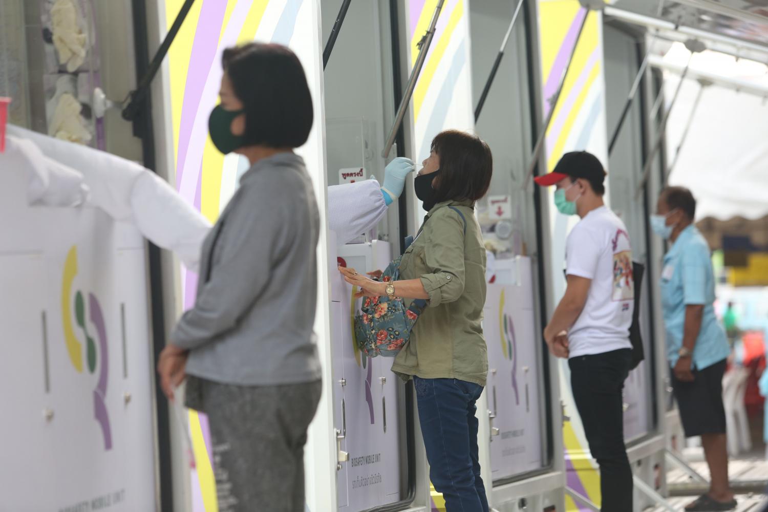 Medics take samples for Covid-19 tests from workers around Pornpat fresh market in Pathum Thani's Thanyaburi district on Wednesday. The market, along with Suchart market in tambon Prachathipat, will be closed until Feb 25. (Photo by Varuth Hirunyatheb)