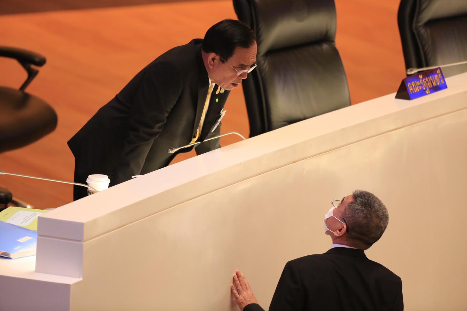 Prime Minister and Defence Minister Prayut Chan-o-cha talks to Deputy Defence Minister Chaichan Changmongkol at the censure debate during which the Defence Ministry was accused of using information operations to cause division and conflicts in society.  (Photo by Pornprom Satrabhaya)