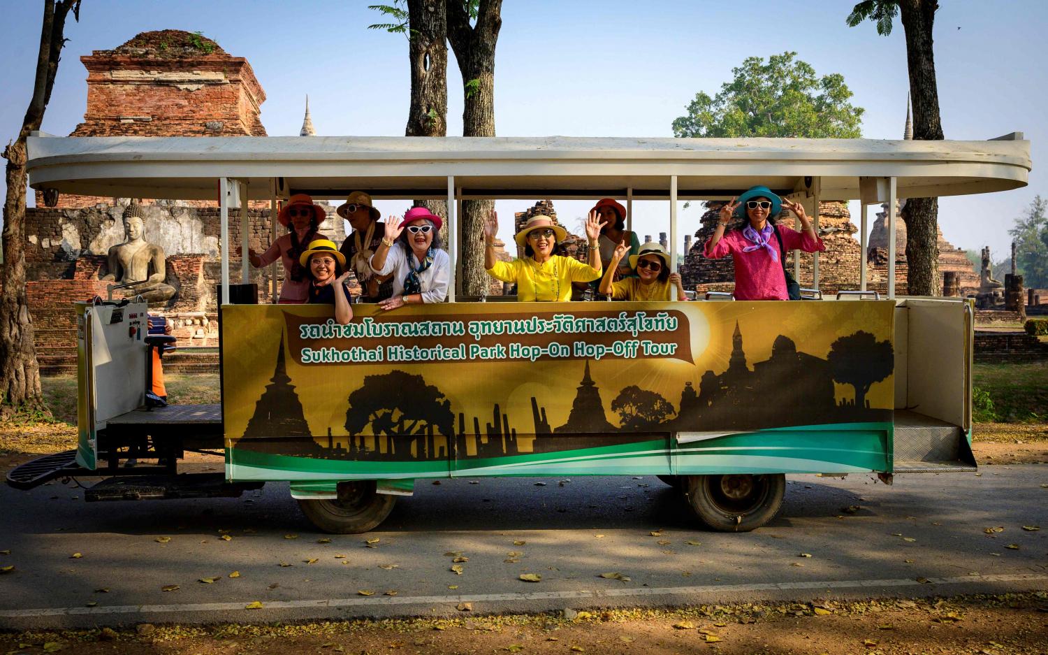 Tourists wave from an electric hop-on hop-off tour bus in Sukhothai Historical Park. Thailand's domestic tourism market is expected to resume in the second quarter this year, driven by the Songkran festival in April. AFP