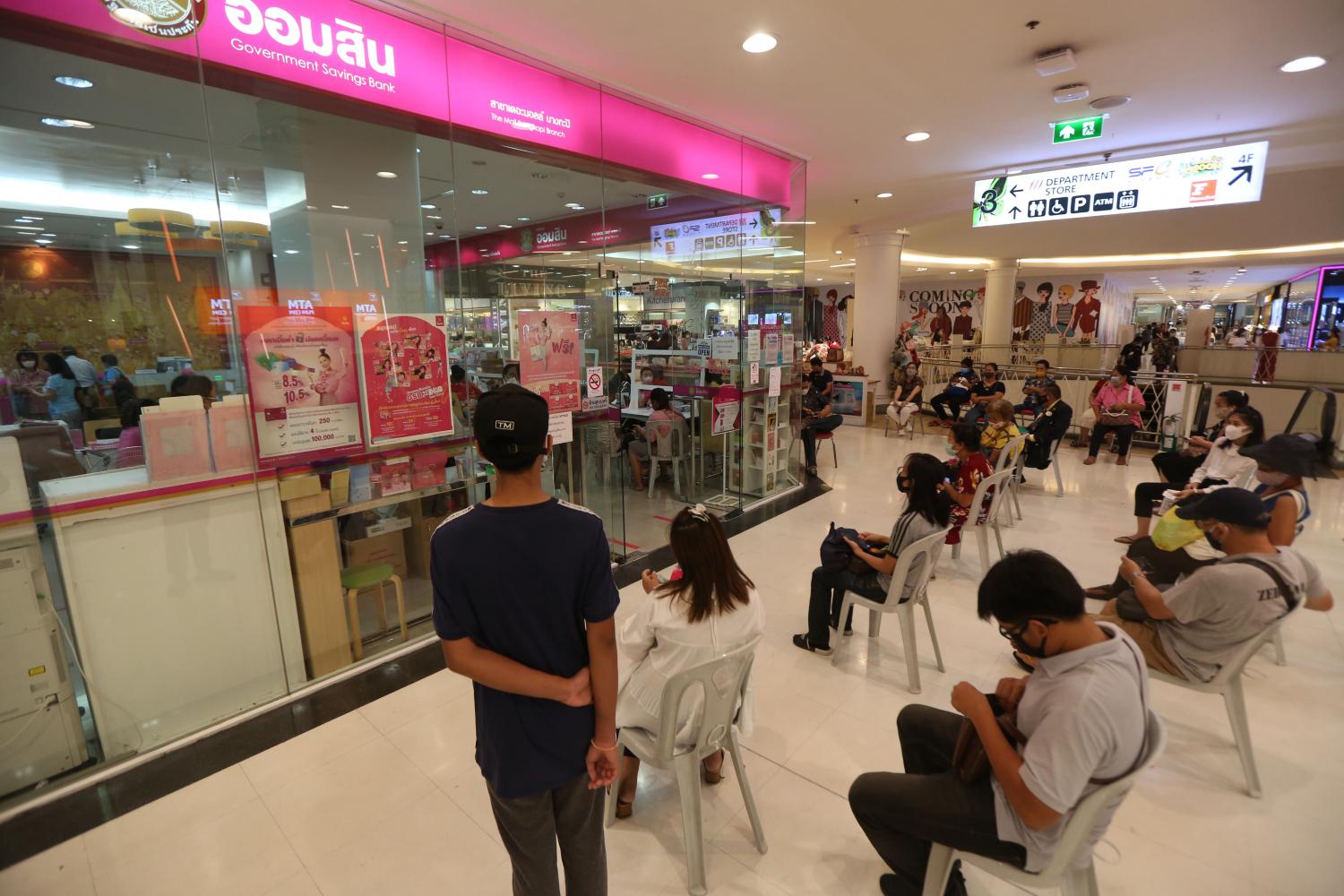 People wait outside a branch of GSB bank. Varuth Hirunyatheb