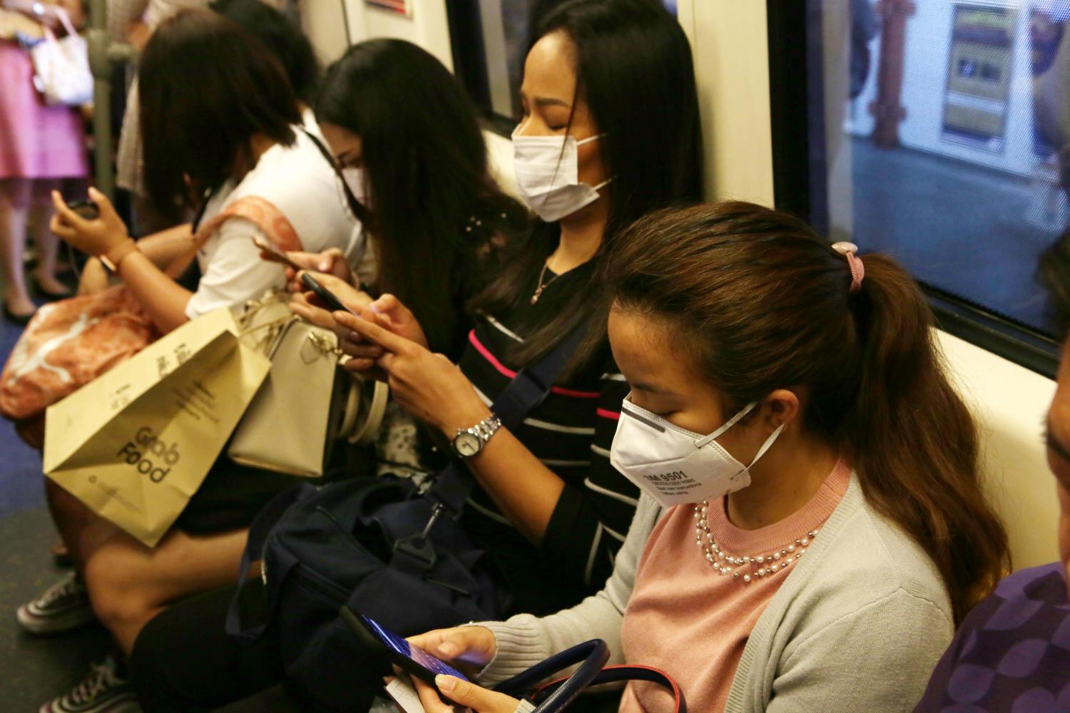 People check their mobile phones while travelling on the skytrain in Bangkok. The DES Ministry is considering linking ID cards to social media registration to combat fake news and support e-commerce. (Photo by Apichit Jinakul)