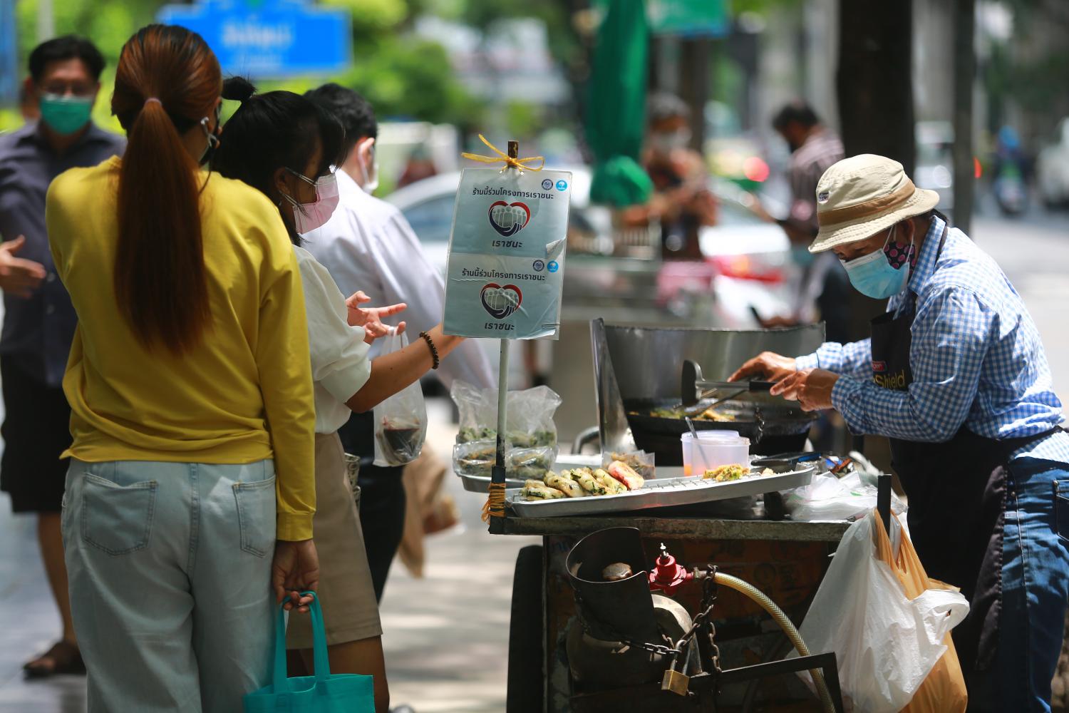 A sign for the Rao Chana (We Win) scheme is seen at a food stall in the Silom area of Bangkok. (Photo by Somchai Poomlard)