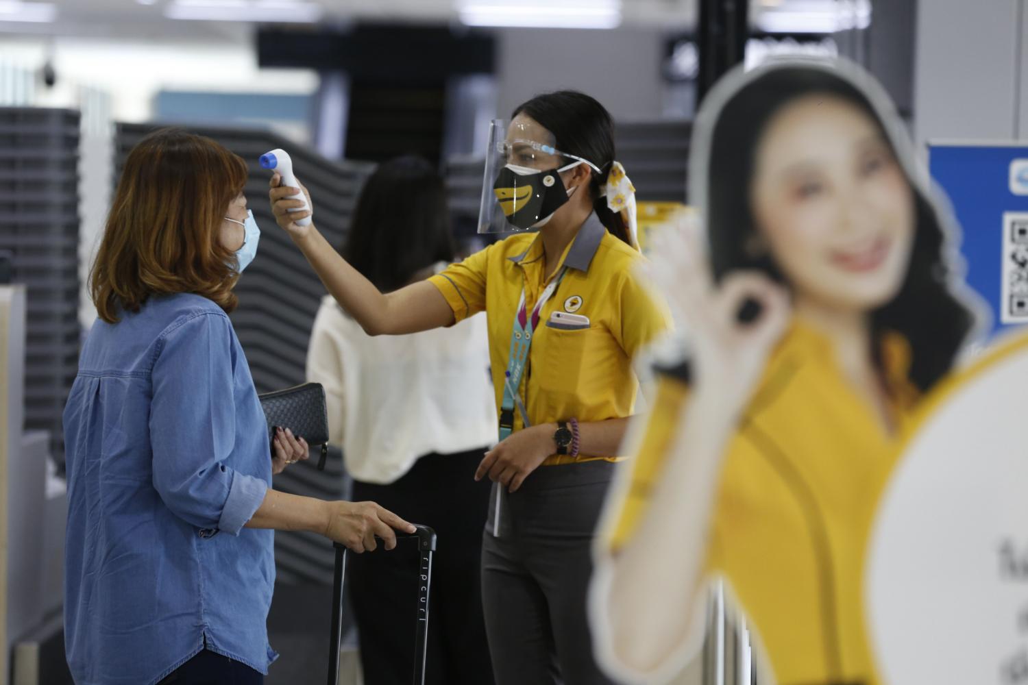 A Nok Air crew member screens passengers during check-in at Don Mueang airport. Pornprom Satrabhaya