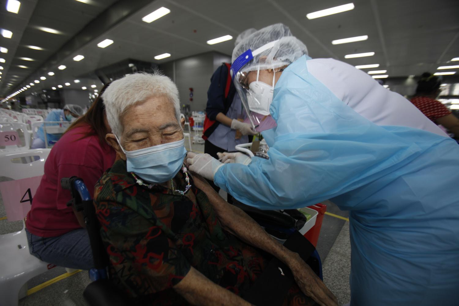 Elderly people flock to Bang Sue Grand Station for Covid-19 shots available for those aged 75 and over. They are allowed one family member or helper each to assist them during the vaccination process. Nutthawat Wicheanbut