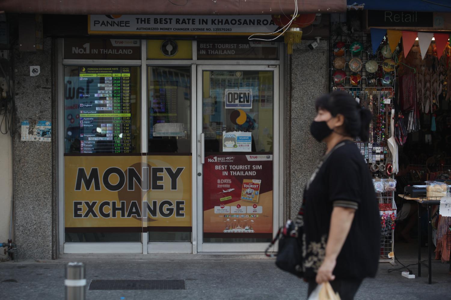 A woman walks past a currency exchange on Khao San Road in Bangkok. (Photo: Nutthawat Wicheanbut) A woman walks past a currency exchange on Khao San Road in Bangkok. (Photo: Nutthawat Wicheanbut)