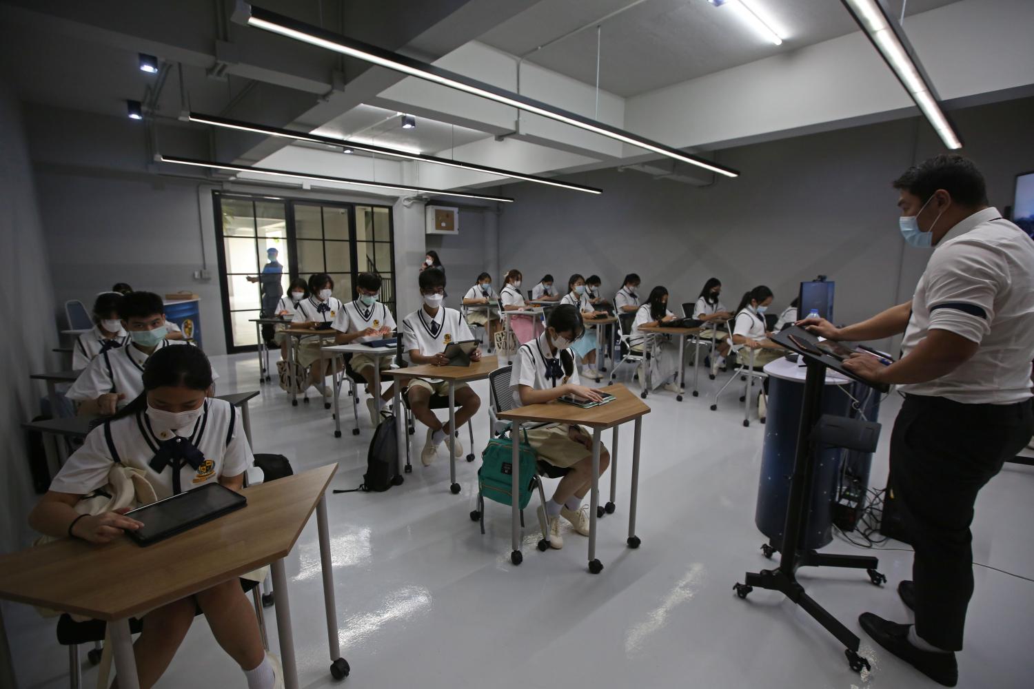 Students sit apart in their classroom at Triamwitpattana School in Bangkok on their first day back at school on Monday, after months of online learning due to the pandemic. Varuth Hirunyatheb