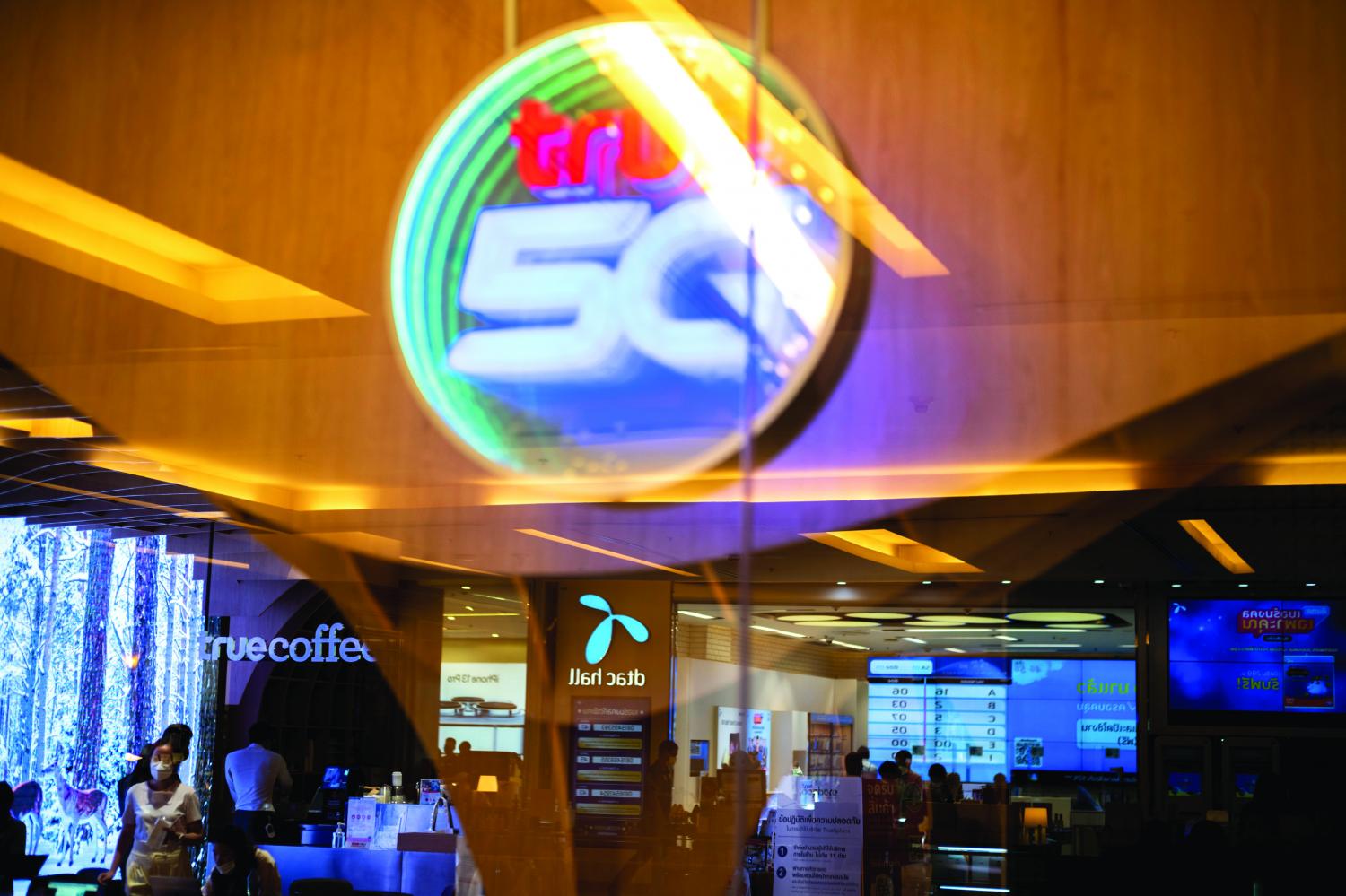 Logos of True Corporation and DTAC are seen at a department store in Bangkok on Monday. (Photo: Reuters) Logos of True Corporation and DTAC are seen at a department store in Bangkok on Monday. (Photo: Reuters)