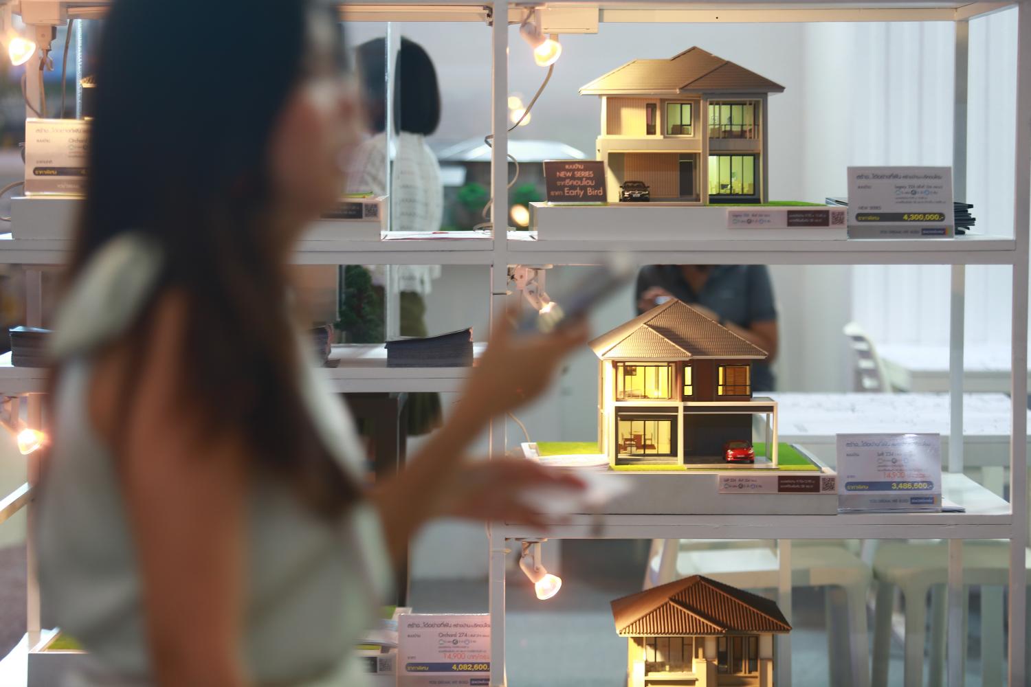 A woman walks past miniature models at a property expo. (Photo: Somchai Poomlard)