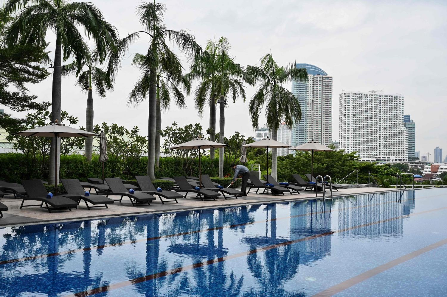 A staff member cleans the pool at a Bangkok hotel. The hotel industry is facing a slowdown because of the temporary suspension of the Test & Go scheme. AFP