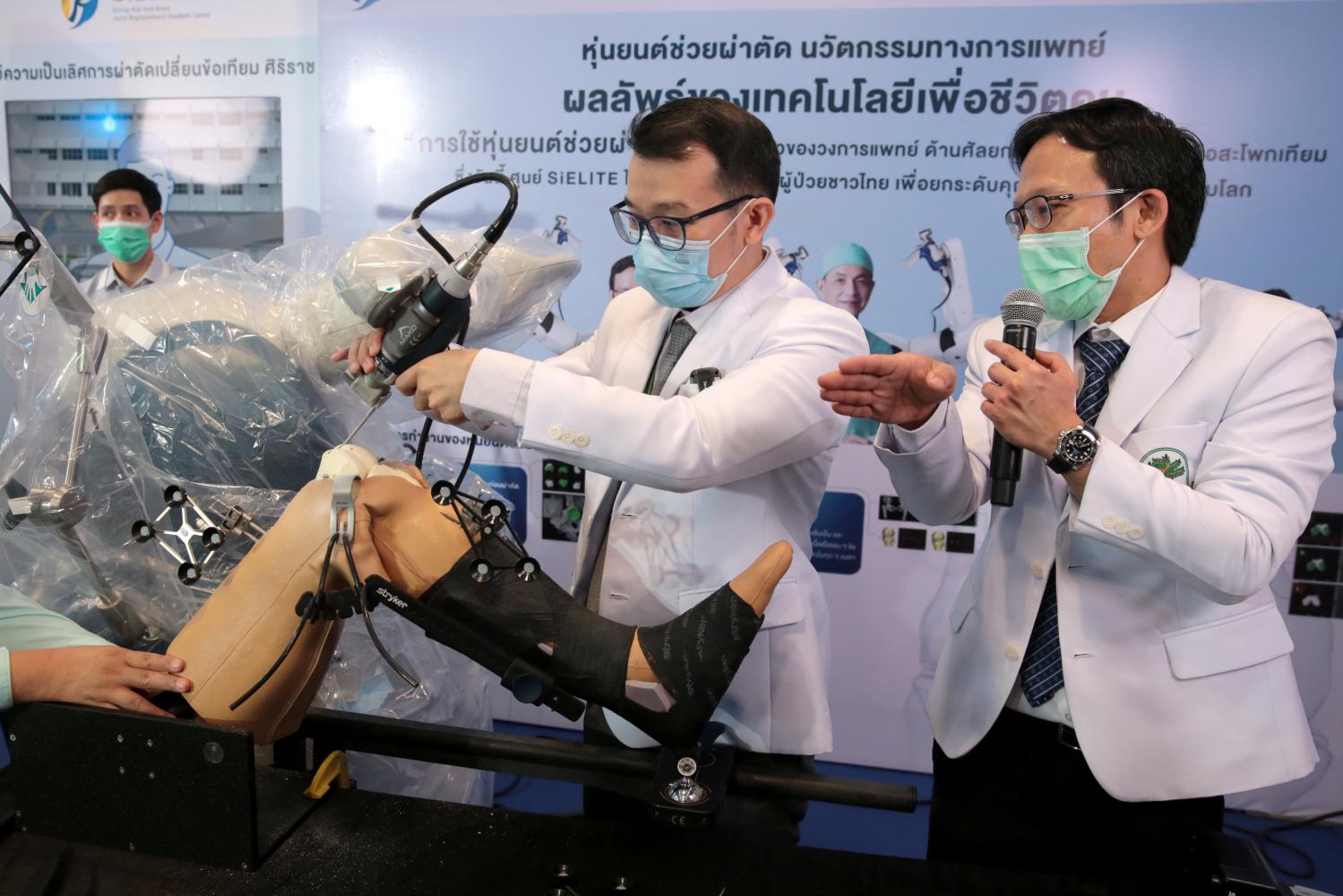 Two doctors at Siriraj Hospital demonstrate robotic knee replacement surgery on a medical dummy. The hospital announced on Monday it successfully replaced the entire knee joint of an elderly patient using a robot. Chanat Katanyu