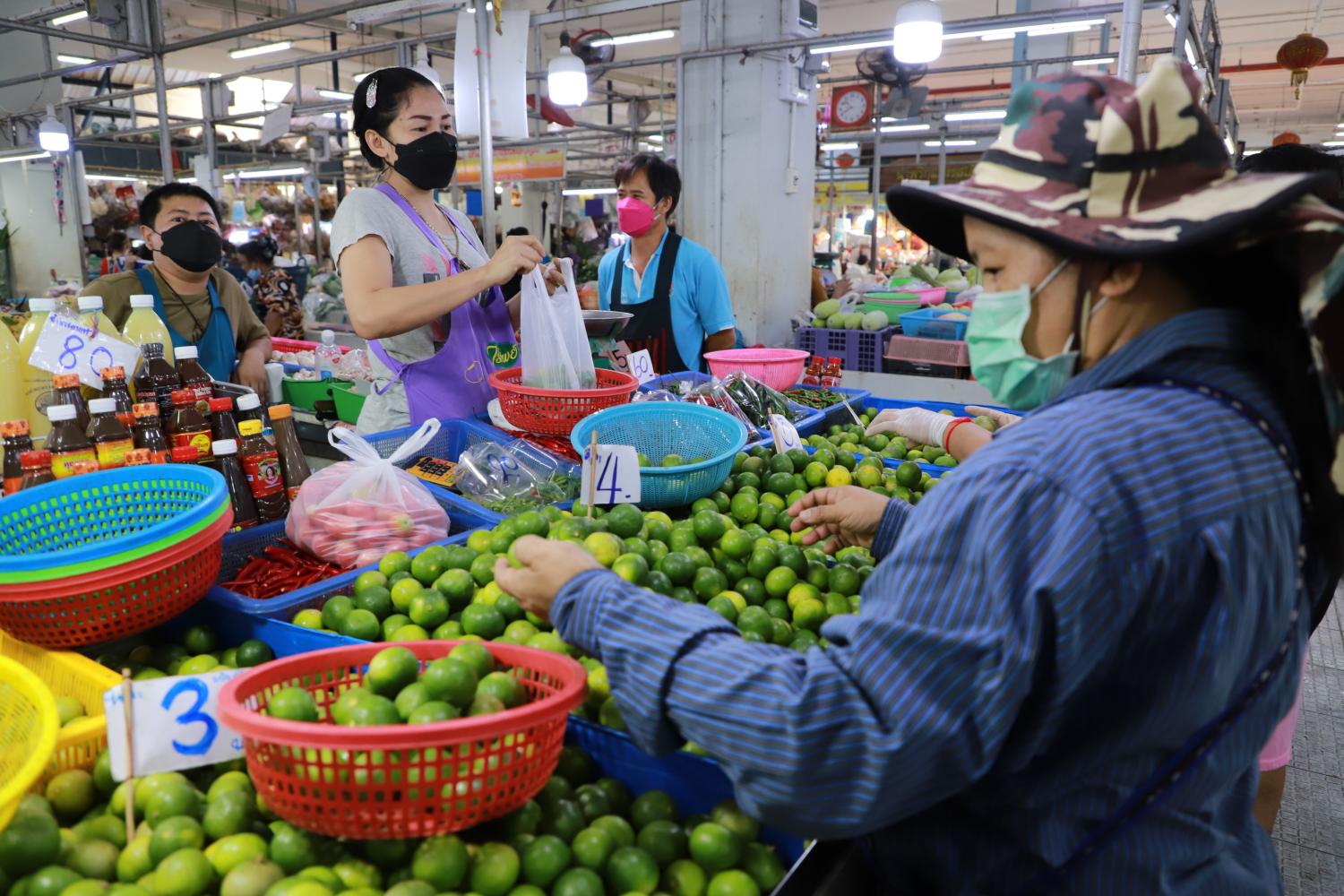 A customer examines limes at a fresh market in Samut Prakan province on Wednesday. The price of limes and of other food products have surged amid concerns over the slow economy. Somchai Poomlard