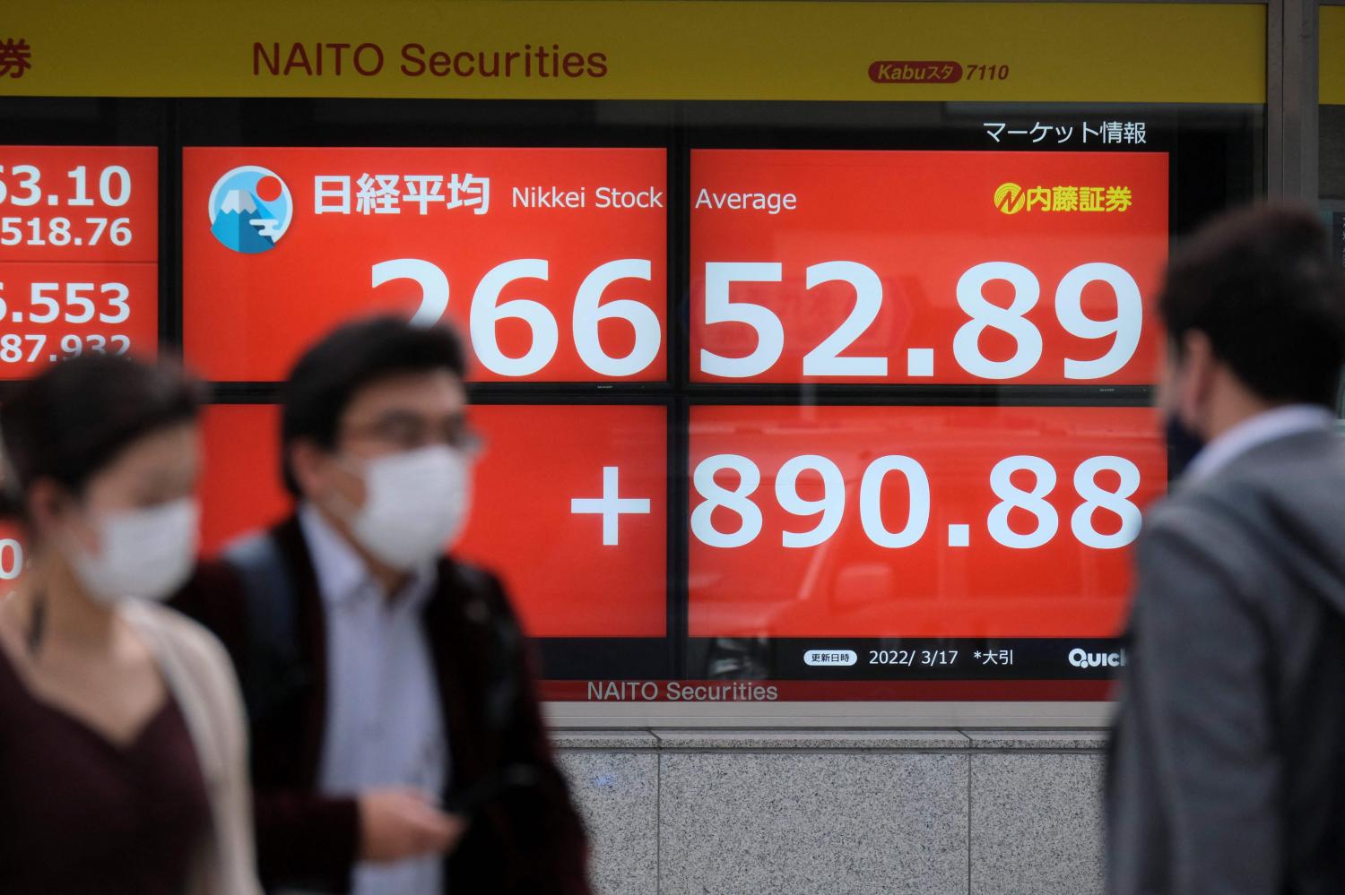 Pedestrians walk past an electronic share price board in Tokyo on Thursday showing the closing numbers on the Tokyo Stock Exchange. (Photo: AFP)