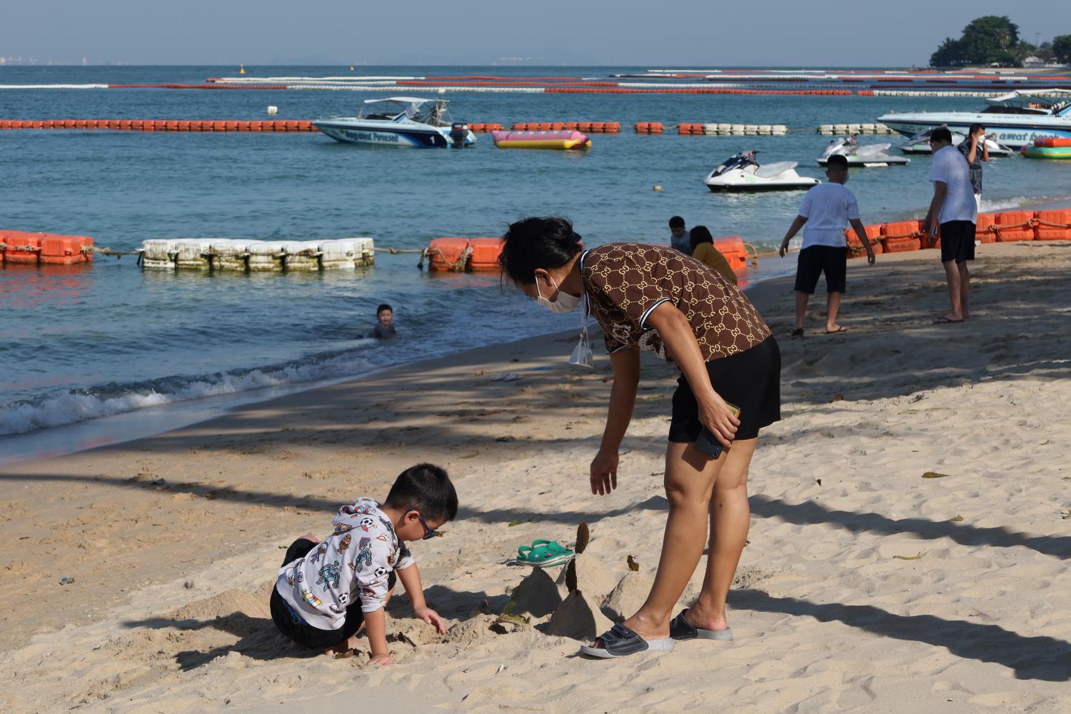 A tourist and child play in the sand at Pattaya beach in Chon Buri province. (File photo)