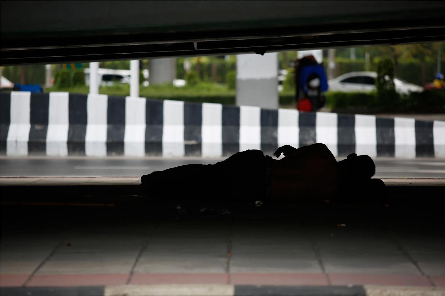 A man lies under the bridge of Lat Phrao intersection in the capital. The issue of homeless people is one that candidates in the Bangkok governor race are being asked to address. (Photo: Arnun Chonmahatrakool)