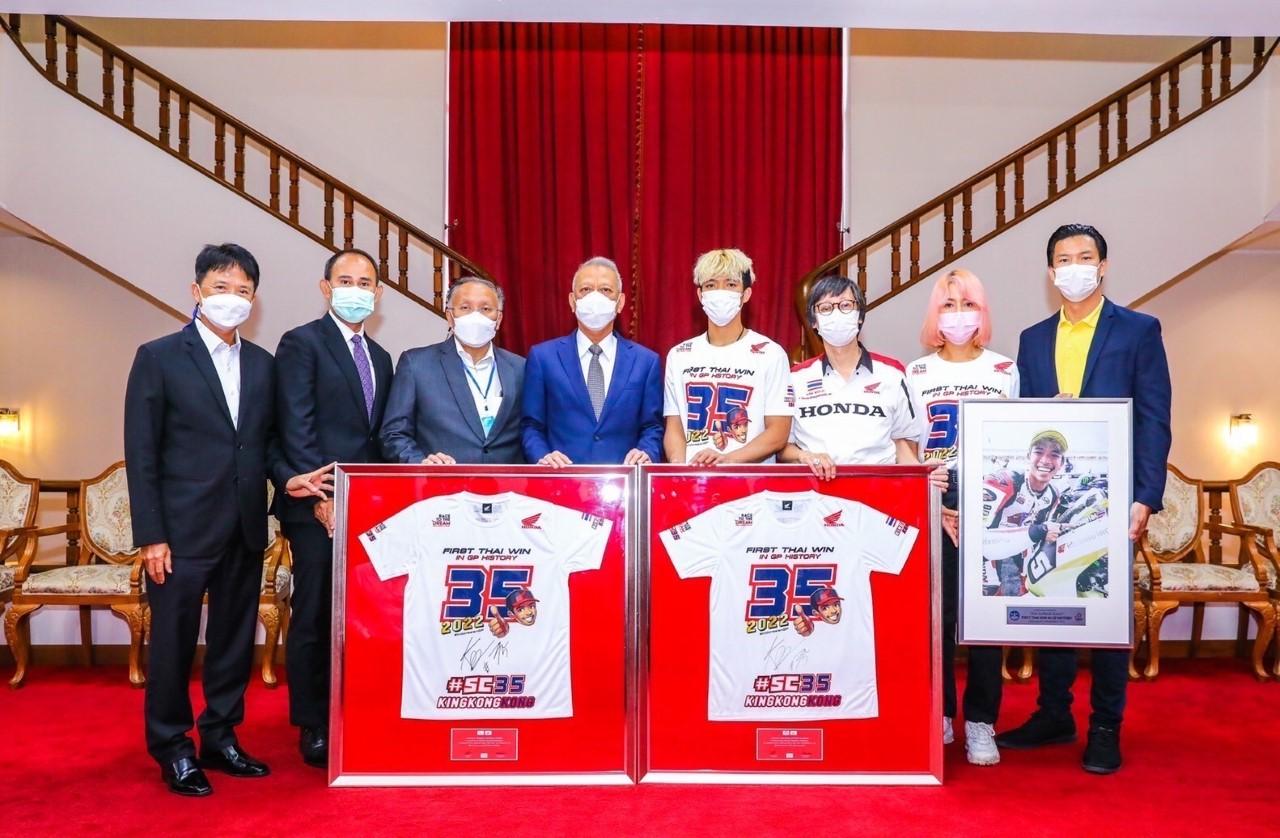 Tourism and Sports Minister Phiphat Ratchakitprakarn (fourth left) receives souvenirs from Moto2 rider Somkiat Chantra, fourth right, at his office on Wednesday.