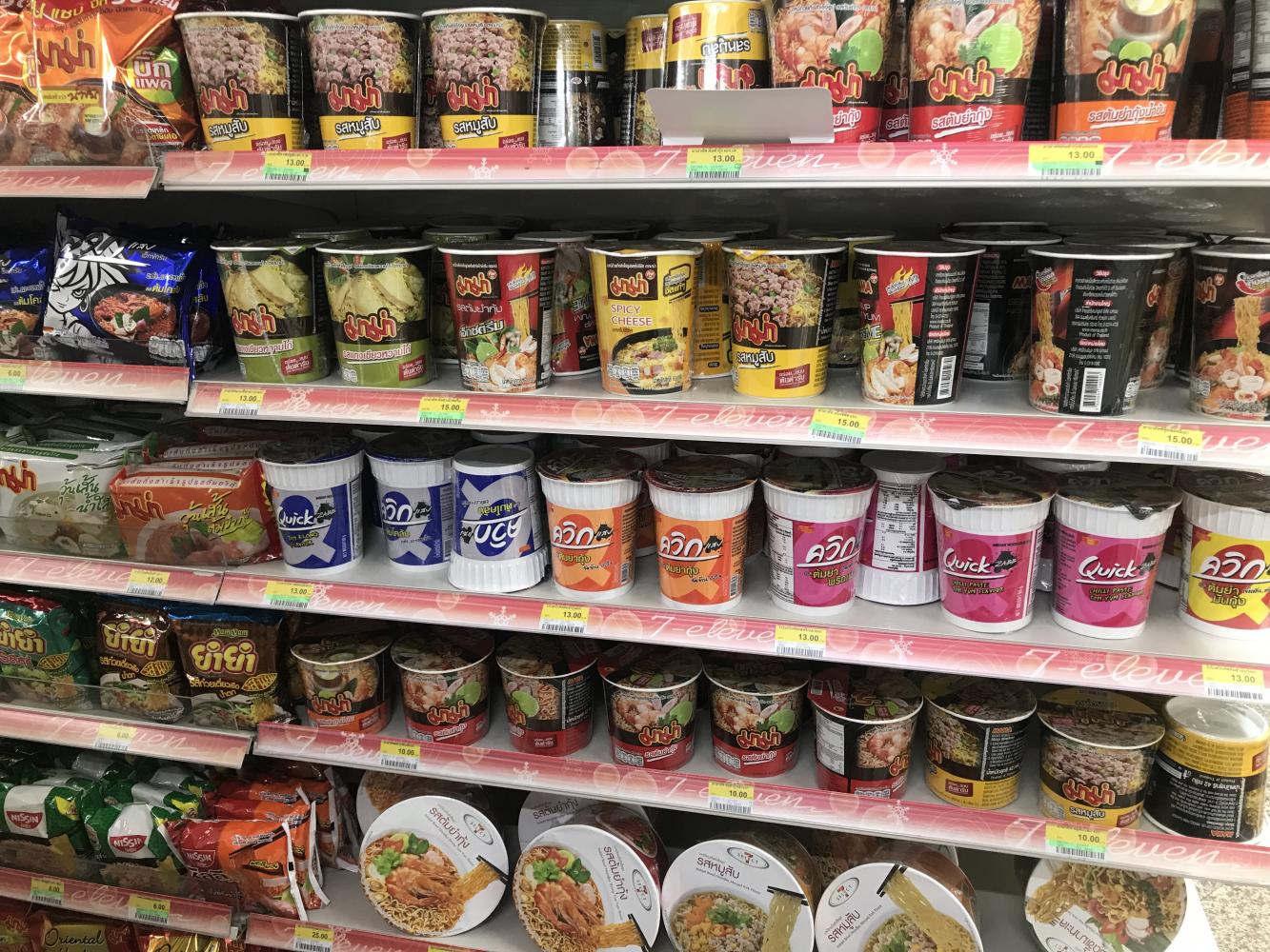 A variety of instant noodle products displayed on shelves at a convenience store in Bangkok. Pattanapong Hirunard