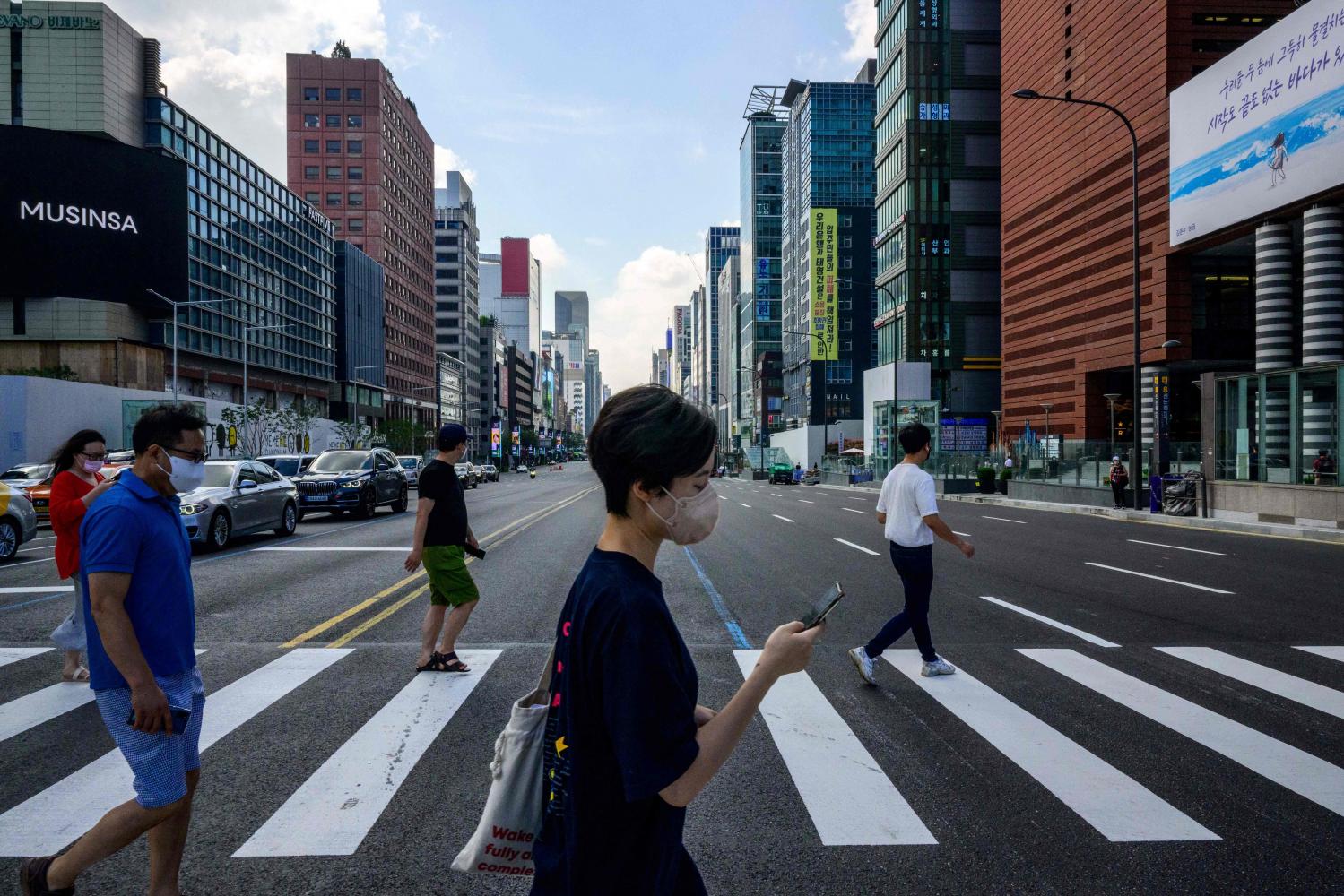 Pedestrians walk across a road in the Gangnam district of Seoul on Aug 12. (Photo: AFP)