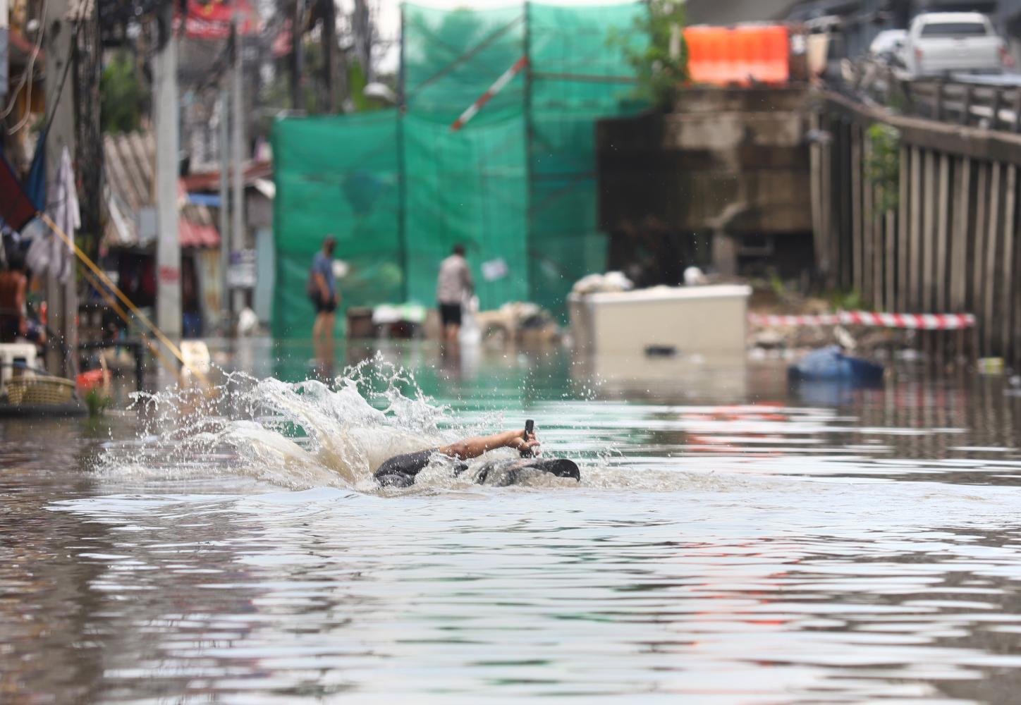 A cyclist stumbles and falls on a flooded street around Bang Bua community along Phahon Yothin Road in Bang Khen district on Wednesday. Hours of widespread downpours, the heaviest in 20 years, left many parts of the city grappling with floods that continued from Tuesday evening until early Wednesday morning. Nutthawat Wicheanbut