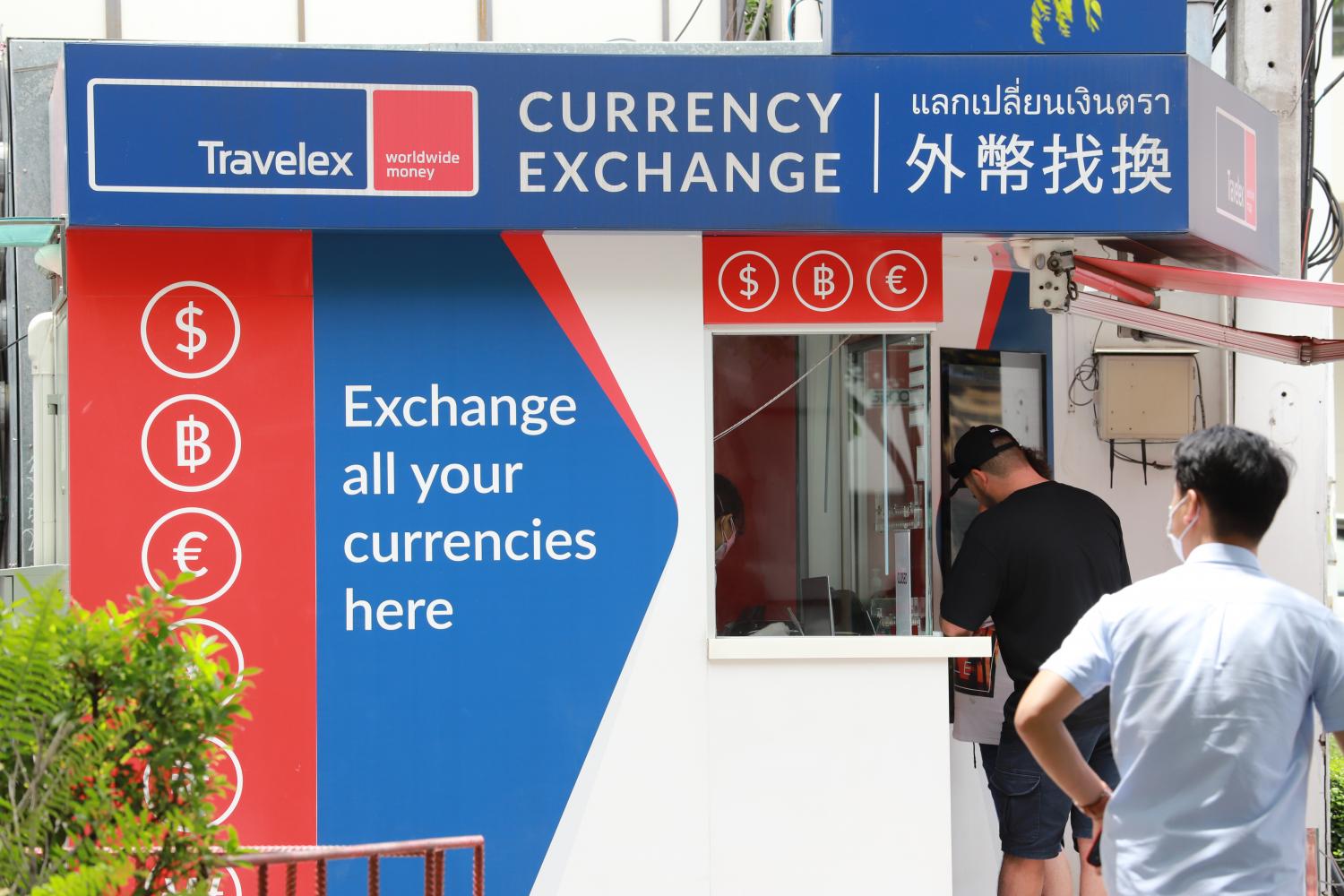 A customer exchanges currency at a branch of Travelex in Bangkok.