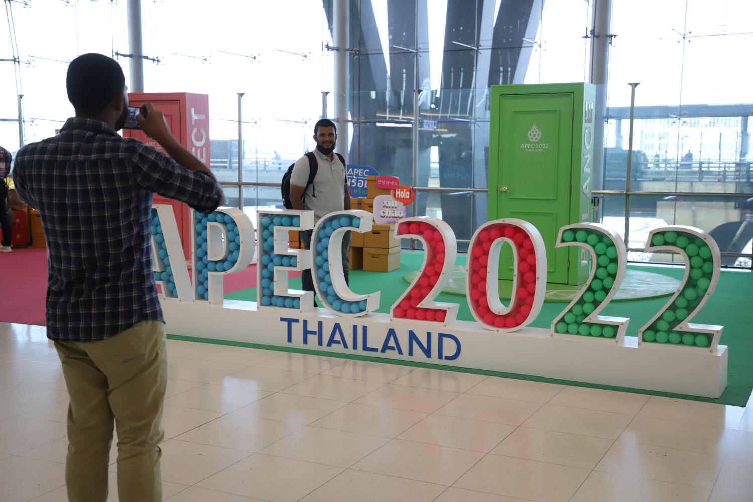 Tourists take photos with a sign for the Apec 2022 summit at Suvarnabhumi airport. (Photo: Varuth Hirunyatheb)