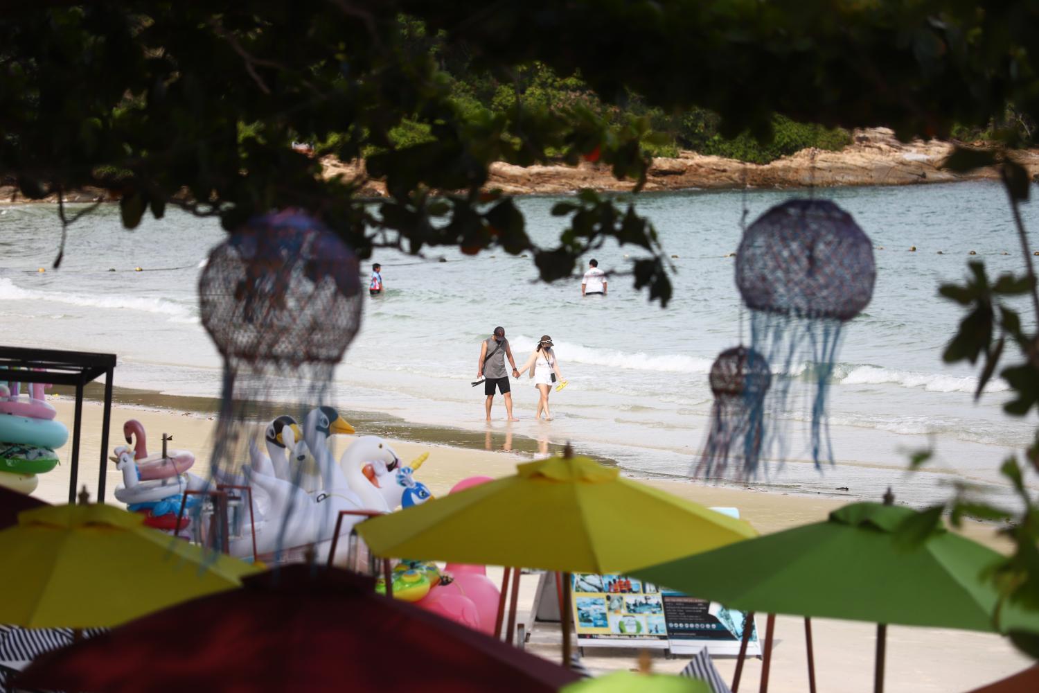 Tourists enjoy a stroll along the beach in Koh Samet in Rayong province. (File photo)