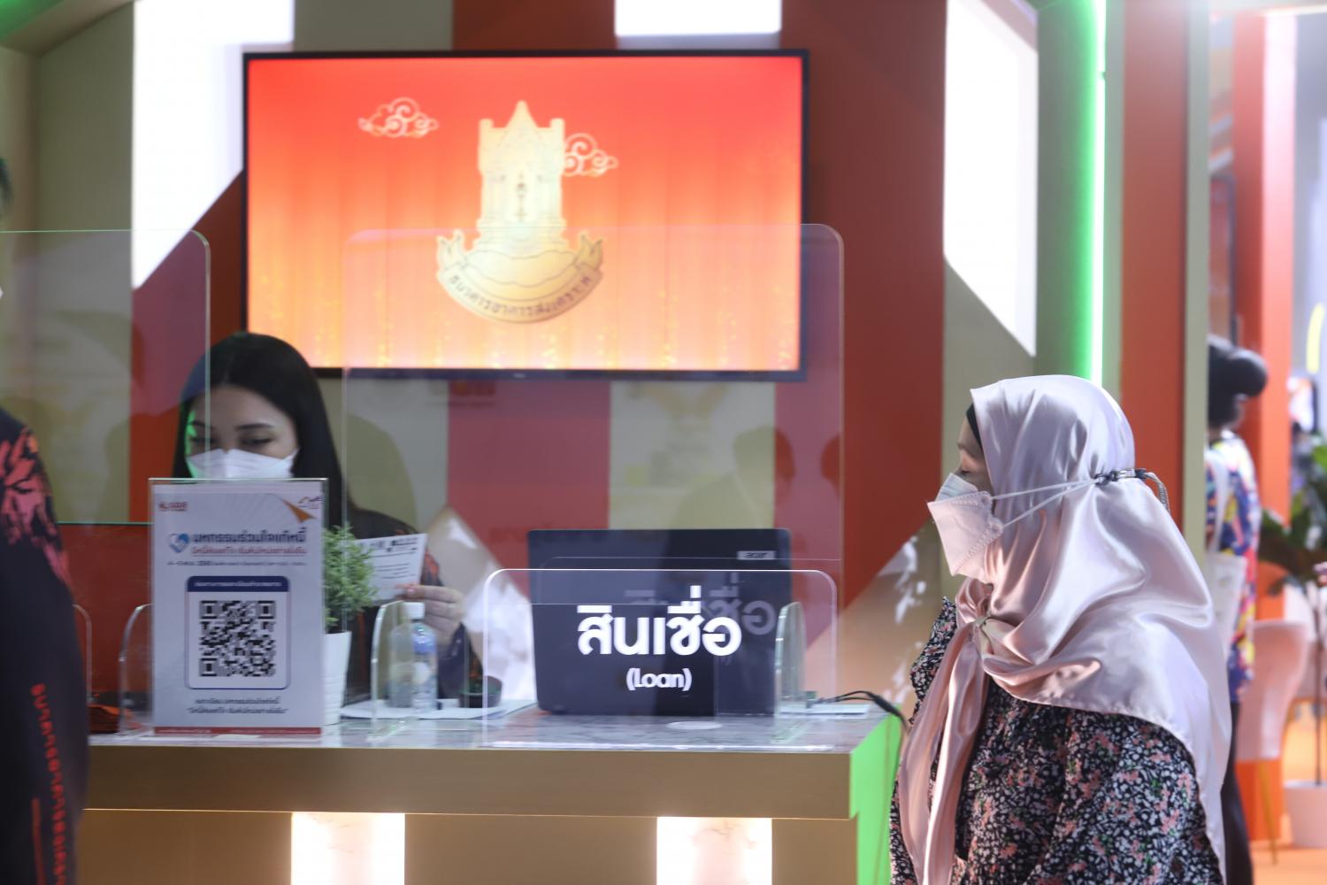 A woman walks past a booth for loans at a fair held in Bangkok. Pornprom Satrabhaya