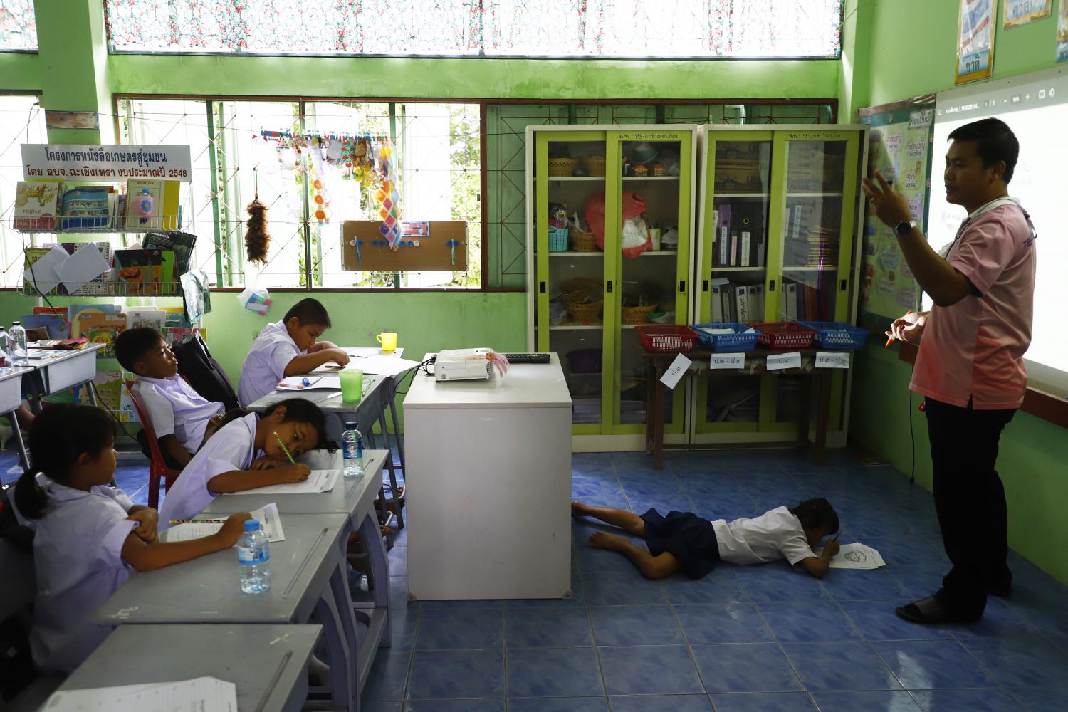 Firing on all cylinders: Krit Chomphra, 34, teaches youngsters to write the Thai alphabet at Ban Nong Heang School in Phanom Sarakham district of Chachoengsao. As the only teacher and staff member there, he has been running himself ragged doing the jobs of janitor, cook, office clerk and headmaster.