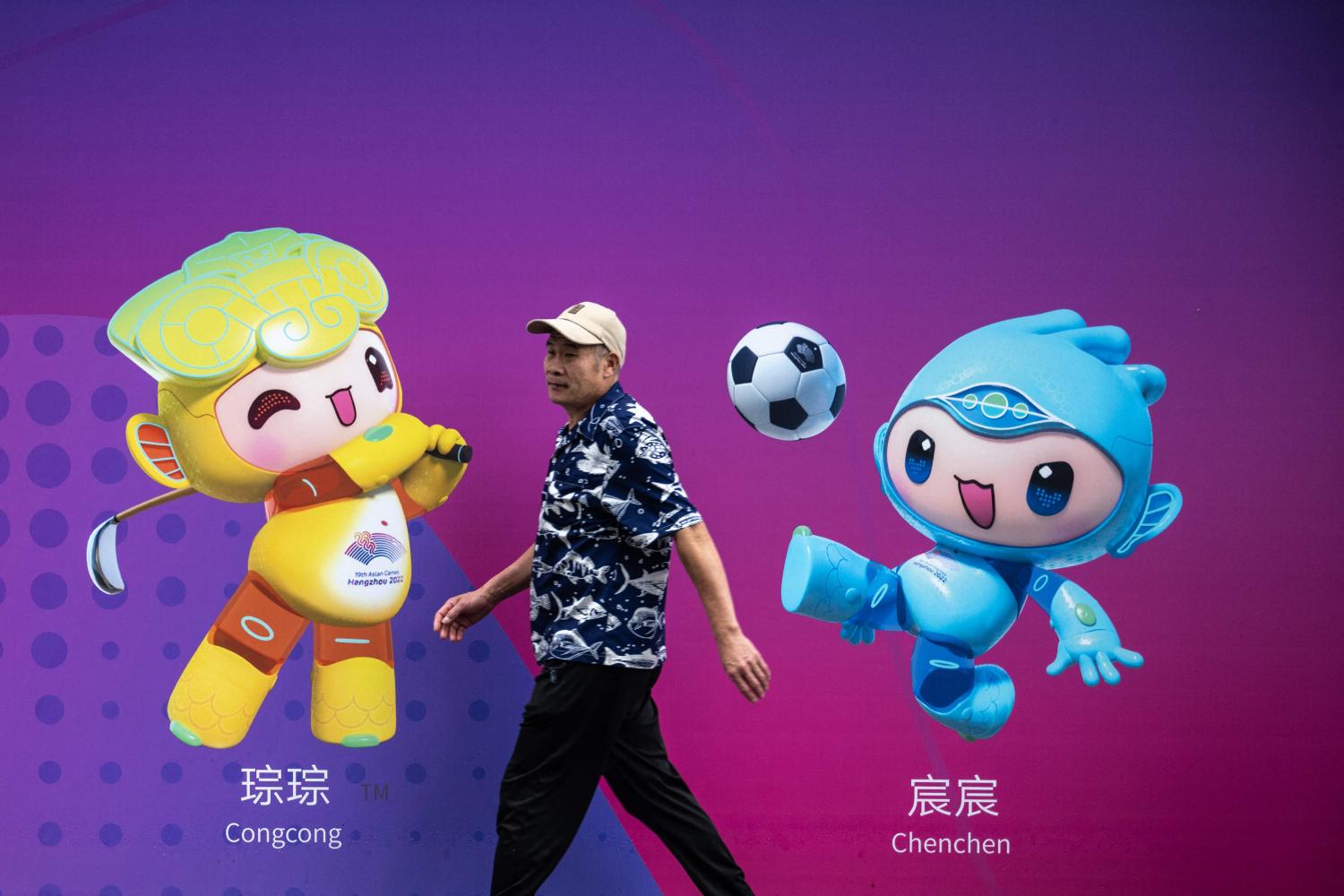 A man walks past a board with 2022 Asian Games mascots Congcong, left, and Chenchen in Hangzhou. (Photo: AFP)