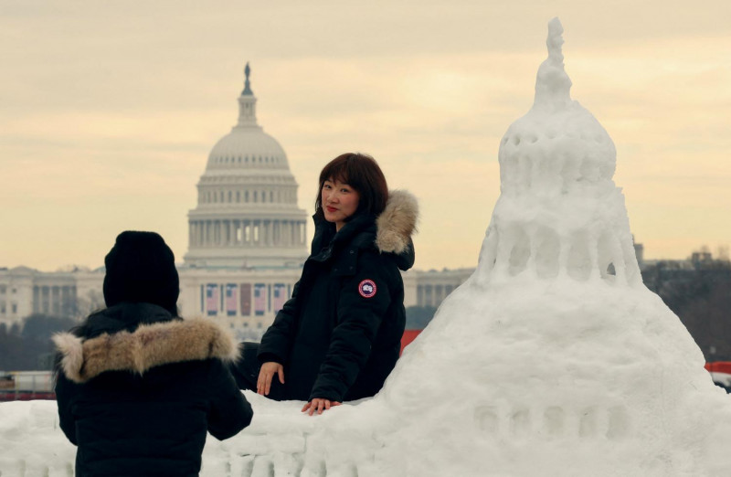 Tourists from China pose for photos with a snow sculpture of the US Capitol with the actual Capitol in the background, decorated with flags for the upcoming inauguration, in Washington. (Photo: Reuters)