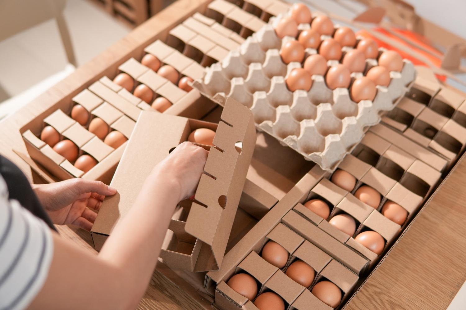 A woman arranges eggs in the wreath packaging.