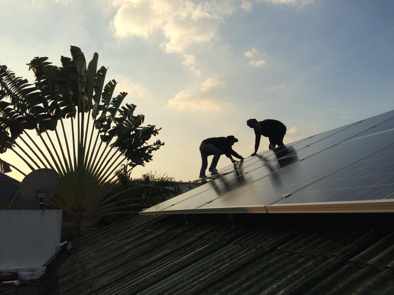 Workers install solar panels on a house. Weeraboon Wisartsakul