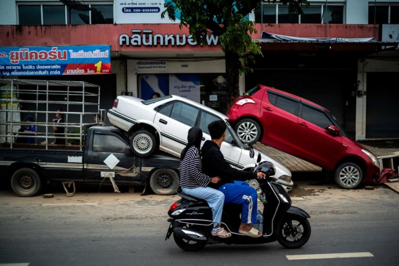 People ride a motorcycle past cars damaged by the flooding in Hat Yai district, Songkhla province, in this photo taken on Nov 27. (Photo: Reuters)