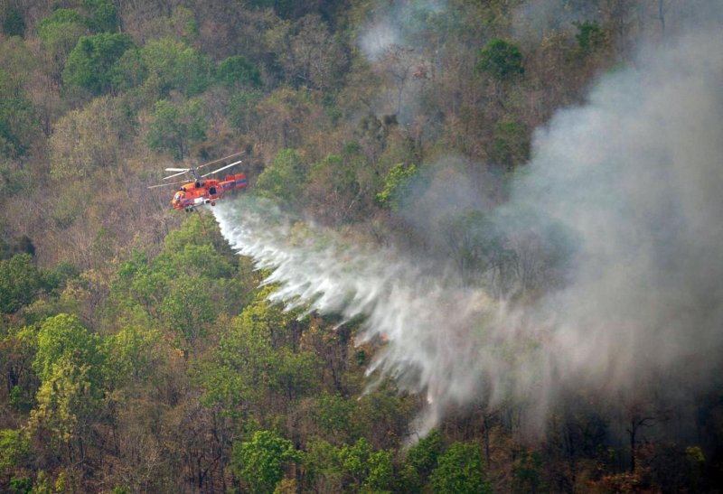 A firefighting helicopter drops water on wildfire hotspots in Chiang Mai. Tourism operators say rampant air pollution is likely to dent tourism sentiment during Songkran.