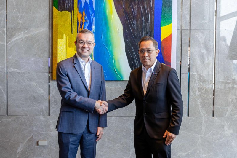 Mr Thirayuth (left) and ML Peekthong shake hands at the signing ceremony marking the launch of their joint venture to develop a network of budget hotels.