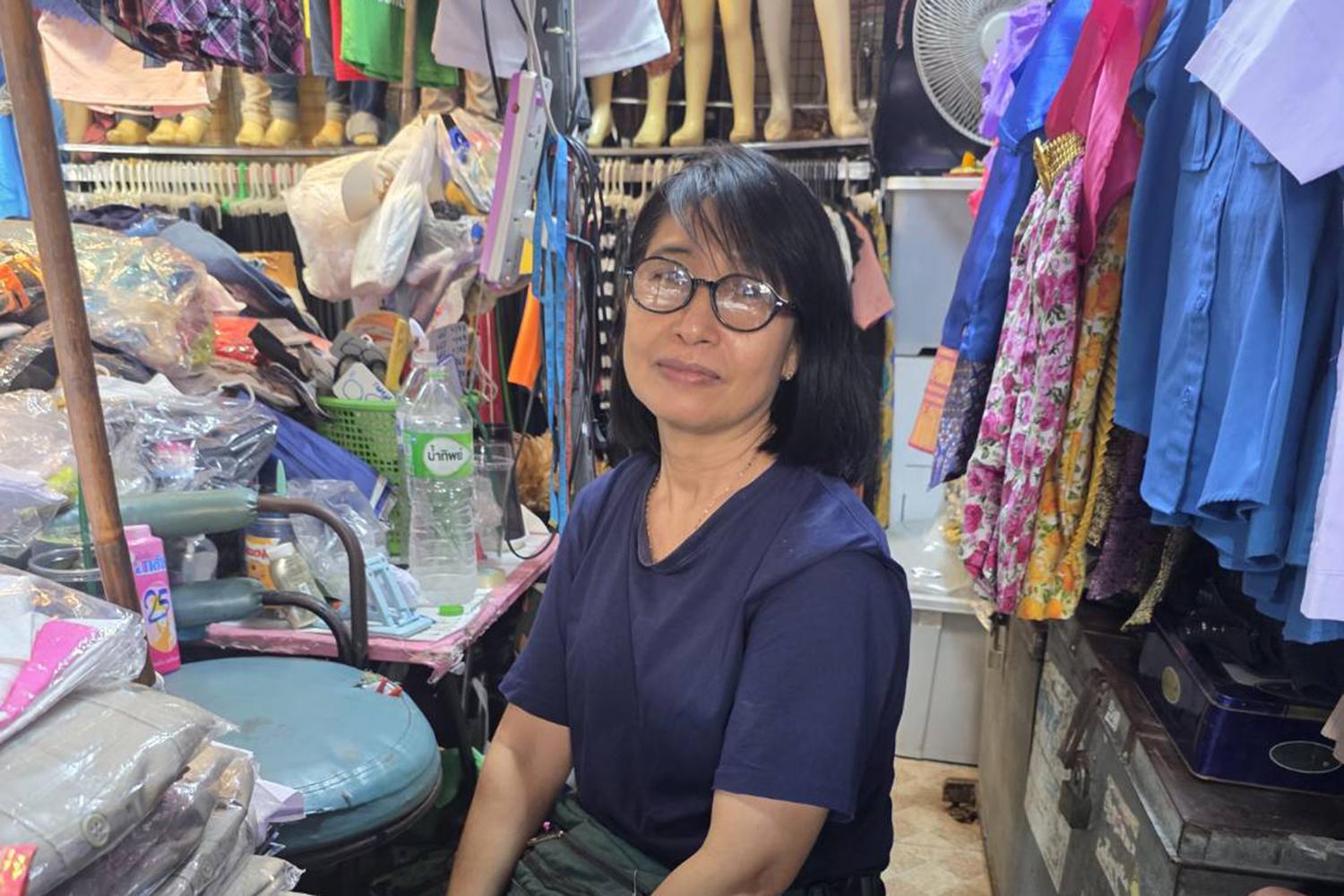 Vendor Pannee Sutsanoh, 55, sells second-hand uniforms at Patthavikorn Market. She says sales of used uniforms have risen slightly this year as families become more cautious about spending. MONGKOL BANGPRAPA