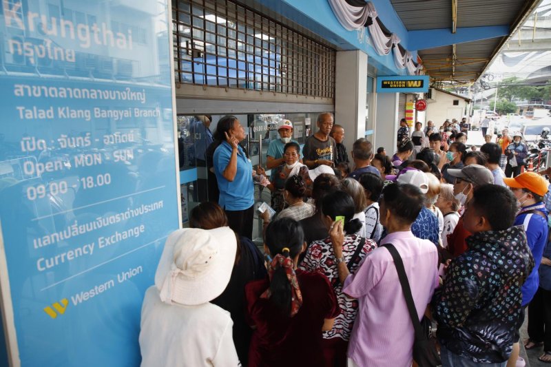Crowds gather outside Krungthai Bank's Bang Yai Market branch in Nonthaburi on Thursday seeking help in registering for the new round of state welfare cards. (Photo: Pattarapong Chatpattarasill)