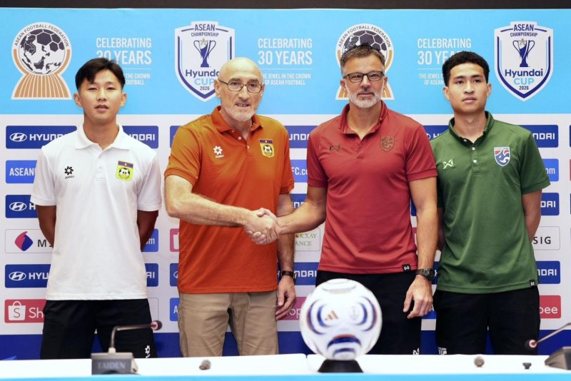 Thailand head coach Anthony Hudson, second right, shakes hands with Laos boss Vladica Grujic during a pre-match press conference.
