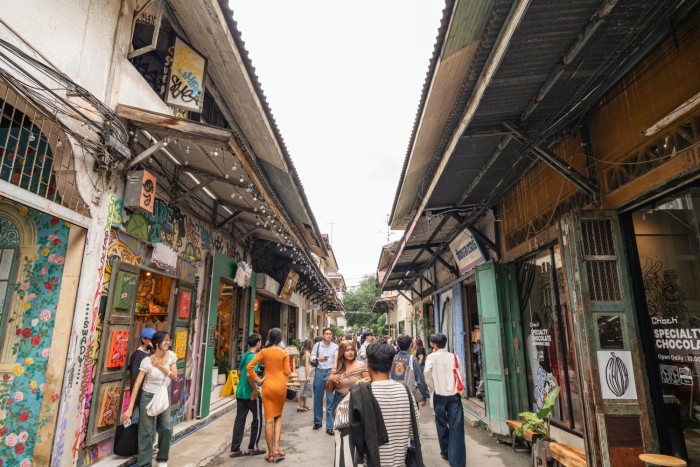 People walking along a narrow, covered street lined with small shops.